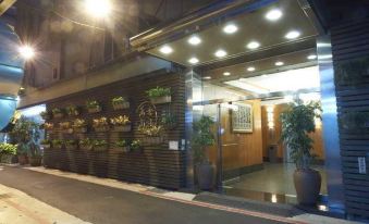 a building with a glass entrance and several potted plants on the wall , creating a cozy atmosphere at Han She Business Hotel