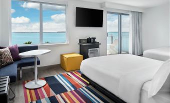 a modern bedroom with a large window , a tv , and a dining table , all connected by a sliding glass door at Aloft Ocean City
