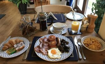 a dining table set with a variety of breakfast items , including plates , cups , and utensils at Church Farm Lodge