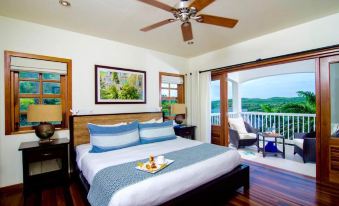 a bedroom with a large bed , blue and white bedding , a tray of food , and a view of the ocean at Residences at Nonsuch Bay Antigua - Room Only - Self Catering