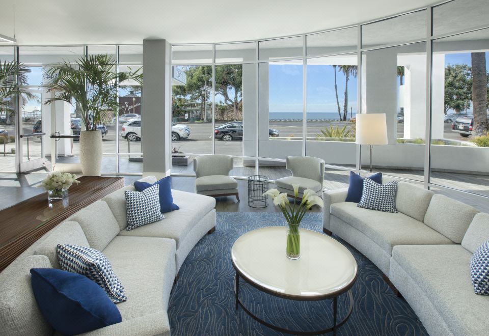 a modern living room with large windows offering a view of the ocean , white couches and chairs arranged around a coffee table at Ocean View Hotel