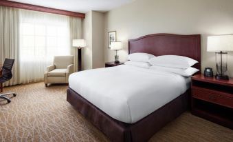 a large bed with white sheets and a purple headboard is in a room with a chair and lamp at DoubleTree by Hilton Sunrise - Sawgrass Mills