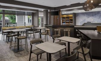 a modern restaurant with various dining tables and chairs , as well as a bar area at SpringHill Suites Tuckahoe Westchester County