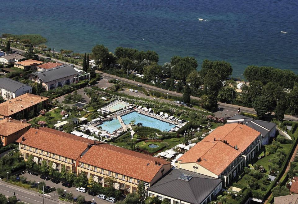 aerial view of a large hotel surrounded by trees and water , with a swimming pool in the foreground at Hotel Caesius Thermae & Spa Resort