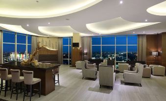 a luxurious hotel lobby with a large window offering a view of the city at night , featuring comfortable seating arrangements and a bar area at Galaxy Hotel Banjarmasin