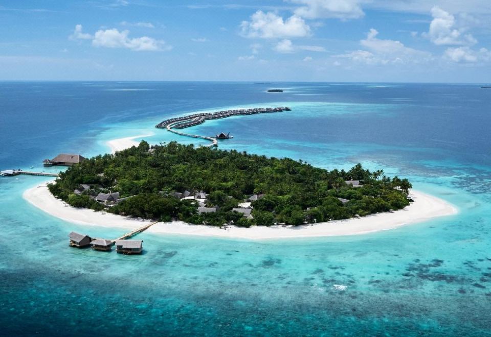 aerial view of a tropical island surrounded by clear blue water , with a bridge connecting to a small island in the distance at Joali Maldives