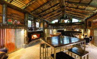 a rustic kitchen with a wooden table and stools , along with a fireplace in the background at Marsden Lake Resort Central Otago