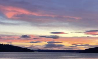 a serene sunset over a lake with pink and blue hues , reflecting the colors of the sky at Lodges on Vashon