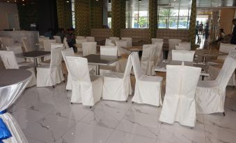 a large room with white chairs and tables , and people sitting at the tables in the background at Hotel 101 Manila