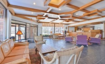 a spacious living room with wooden ceiling beams , comfortable furniture , and large windows , giving it an open and inviting atmosphere at Best Western Prairie Inn  Conference Center
