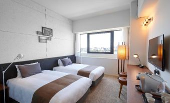 a modern hotel room with two beds , white walls , and large windows , along with other amenities at Kawasaki King Skyfront Tokyu Rei Hotel