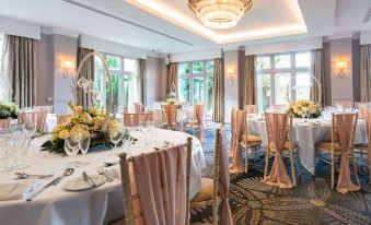 a large dining room with tables set for a formal dinner , complete with white tablecloths , gold chairs , and flowers at Mercure Blackburn Dunkenhalgh Hotel & Spa