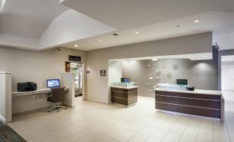 a modern office reception area with a desk , chairs , and a tv mounted on the wall at Residence Inn Stockton