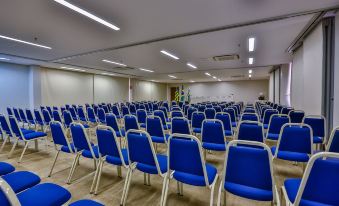 a large conference room with rows of blue chairs arranged in a symmetrical fashion , ready for an event at San Marino Suites Hotel by Nobile