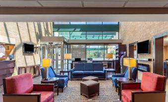 a modern hotel lobby with various seating arrangements , including couches and chairs , under the open ceiling at Comfort Suites Oakbrook Terrace Near Oakbrook Center