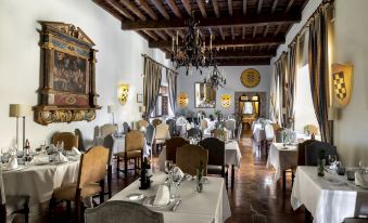 a well - decorated dining room with tables and chairs arranged for a group of people to enjoy a meal together at Parador de Jarandilla