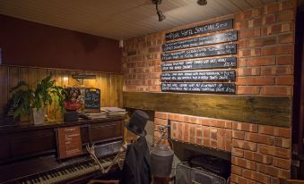 a brick wall with a chalkboard menu and a fireplace , featuring a piano in the background at The Peak Hotel