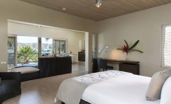 a modern bedroom with a large bed , a desk , and a door leading to an outdoor area at South Point Antigua
