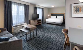 a modern hotel room with a bed , desk , and window , all set against a gray carpet at Homewood Suites by Hilton Newburgh-Stewart Airport