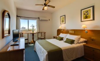 a hotel room with a comfortable bed , a tv , and a desk with a computer at Hotel Royal