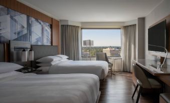 a modern hotel room with two beds , a window offering a view of the city , and wooden flooring at Tysons Corner Marriott