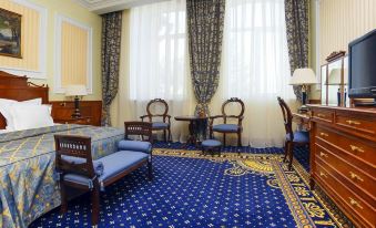a hotel room with a blue and yellow carpeted floor , a double bed , a television , and a dresser at Hotel Parus