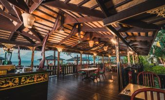 an outdoor dining area at a restaurant , with wooden tables and chairs arranged for guests to enjoy their meal at Berjaya Tioman Resort