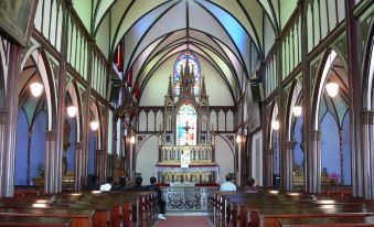 a church interior with wooden pews , stained glass windows , and a large stained glass altar at Nagasaki Nisshokan