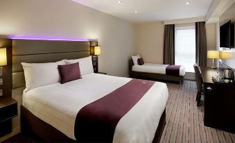 a hotel room with two beds , one of which is made up with a purple blanket and white bedding at Premier Inn Whitehaven