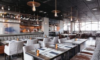 a modern restaurant with wooden tables and chairs , white tablecloths , and pendant lights hanging from the ceiling at Langley Hotel Tignes 2100