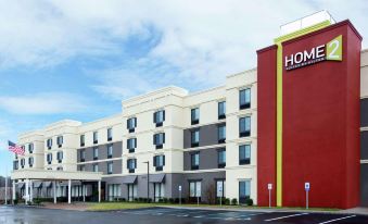 a hotel with a large red and white building , possibly a hotel , situated on a street corner at Home2 Suites by Hilton Long Island Brookhaven