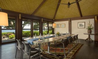 a dining room with a long wooden table , surrounded by chairs , and a ceiling fan at Jeeva Klui Resort