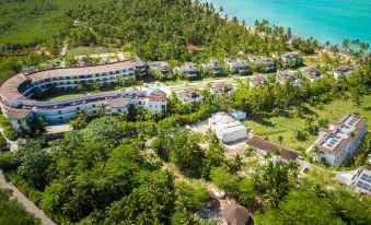 a bird 's eye view of a resort with green trees , buildings , and the ocean in the background at Small Luxury Hotels of the World - Sublime Samana Hotel & Residences