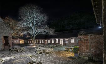 a nighttime scene of a building with a large tree in front of it , surrounded by tables and chairs at Spread Eagle Inn