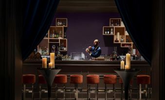 A woman stands in front of the bar at an upscale restaurant with large glass panels on both sides at The Portman Ritz-Carlton, Shanghai