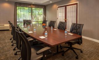 a conference room with a large wooden table surrounded by black chairs and water bottles at SpringHill Suites Centreville Chantilly
