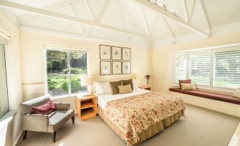 a large bedroom with a king - sized bed , a couch , and a window overlooking a grassy field at Cape Lodge