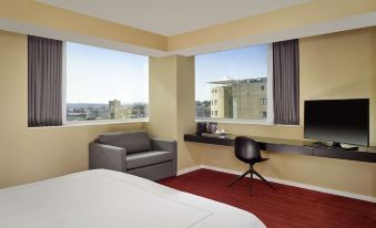 a modern hotel room with a bed , desk , and large window offering a view of the city at Park Plaza Leeds
