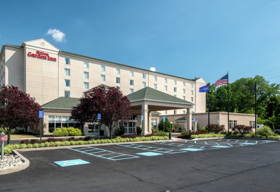 a hotel with a large parking lot and an american flag on the side of the building at Hilton Garden Inn Philadelphia/Ft. Washington