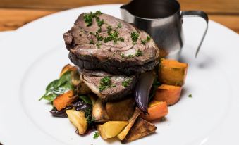 a plate of food on a dining table , consisting of steak and vegetables , accompanied by a sauce at Wonderland Makarora Lodge