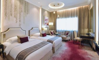 a modern hotel room with two beds , a desk , and a window , all decorated in white and red at Movenpick Hotel Bahrain