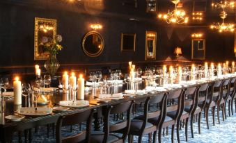 a long dining table with multiple lit candles , wine glasses , and place settings in a dark room at BrookLodge & Macreddin Village