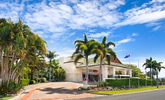 a hotel with a red roof and palm trees is shown in the image at Mercure Gold Coast Resort