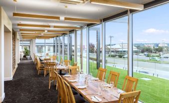 a large dining room with wooden tables and chairs arranged for a group of people to enjoy a meal together at Mercure Goulburn
