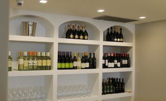 a white wine shelf with various bottles of wine and glasses arranged on it , along with an arched design at B&B Hotel Trapani Crystal