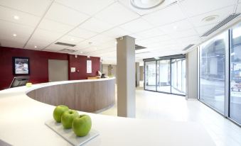a modern office lobby with a reception desk , three green apples on a tray , and large windows at Campanile Paris Est - Bobigny