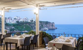 a restaurant with tables set for dining , overlooking the ocean and a cliff in the distance at Falcon Hotel