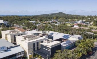 a bird 's eye view of a residential area with buildings and trees , under a clear blue sky at YHA Byron Bay