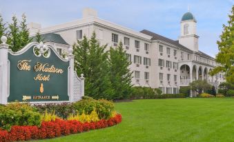 a large white building with a green and white sign in front of it , surrounded by a grassy area at The Madison Hotel