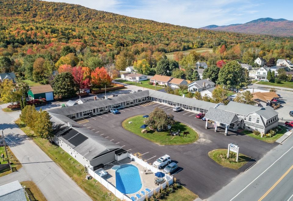aerial view of a hotel with a pool and parking lot , surrounded by trees and mountains at Top Notch Inn